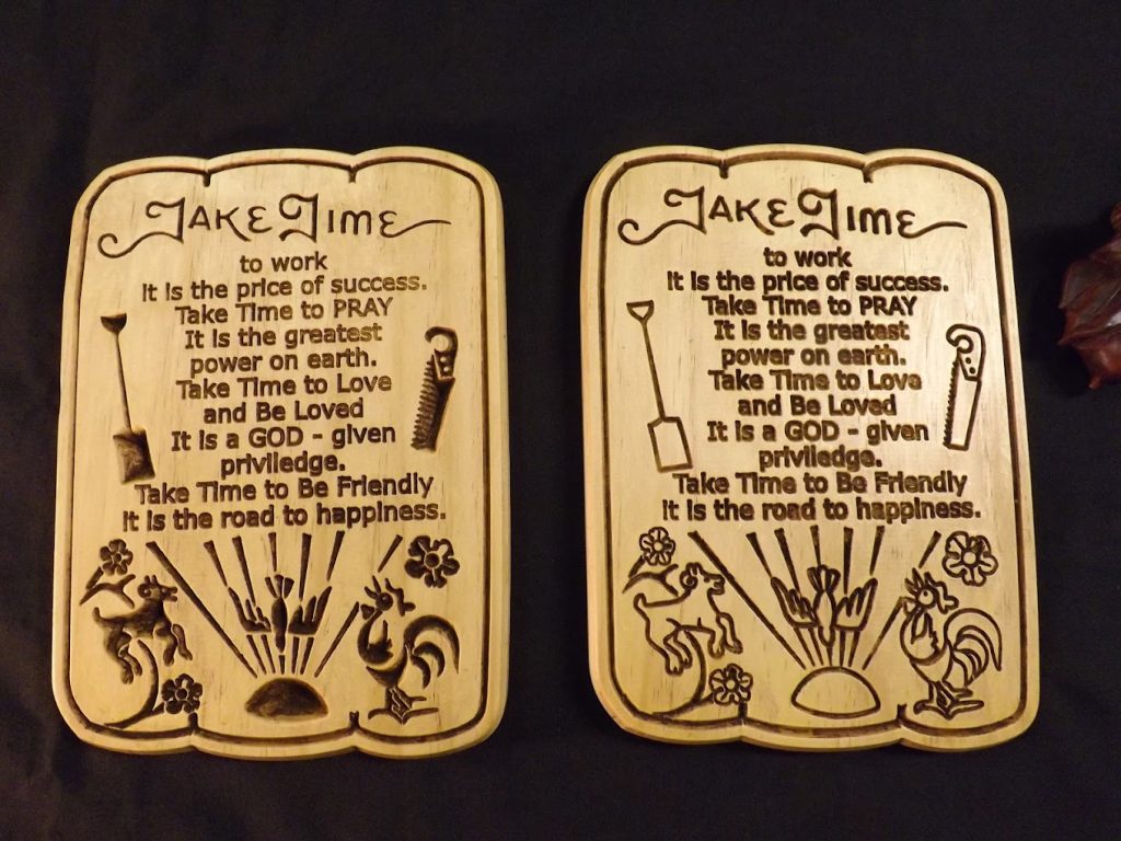 Two engraved wooden plaques display identical motivational quotes and images of a rooster, flowers, and garden tools.